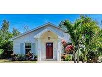 White house with red door, landscaping, and palm trees at 606 19Th W Ave, Palmetto, FL 34221