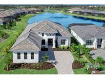 Luxury home with lake view, paver driveway, and landscaped yard at 8367 Sea Glass Ct, Sarasota, FL 34240