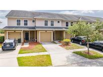 Tan townhouses with attached garages and landscaped yards at 5809 Leopardstown Dr, Tampa, FL 33610