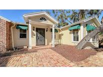 Cute yellow house with a charming front porch and brick walkway at 8440 Midnight Pass Rd, Sarasota, FL 34242