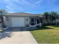 Single-story home with a white garage door, landscaping, and driveway at 9359 Casa Grande Ave, Englewood, FL 34224