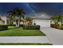Single-story home with gray siding, white garage door, and manicured landscaping under a night sky at 12117 Whisper Lake Dr, Bradenton, FL 34211