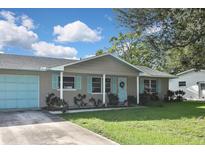 Tan house with light blue accents, a double garage door, and a manicured lawn at 3111 Taunton W Dr, Bradenton, FL 34205