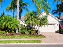 Single-story home with light beige walls, lush landscaping, and a two-car garage at 7131 Sandhills Pl, Lakewood Ranch, FL 34202