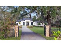 White two-story house with gated entry, manicured lawn, and mature trees at 15125 Waterline Rd, Bradenton, FL 34212