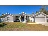 Single-story home with gray exterior, two-car garage, and landscaped lawn at 2155 Jagust Rd, North Port, FL 34288