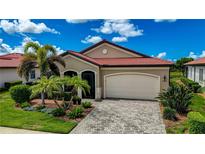 One-story home with a red tile roof, landscaping, and a paved driveway at 23463 Copperleaf Dr, Venice, FL 34293