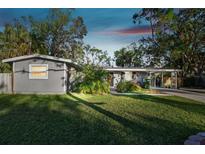 Gray house with landscaped lawn, driveway and carport at 1100 27Th W Ave, Palmetto, FL 34221