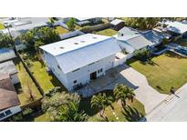 Aerial view of a two-story house with metal roof, driveway, and landscaped yard at 1790 Ezelle Ave, Largo, FL 33770