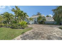 Two-story house with light blue brick exterior, landscaping, and paver driveway at 4892 Peregrine E Pt, Sarasota, FL 34231