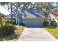 Gray house with teal door, two-car garage, and nicely landscaped yard at 6804 Arbor Oaks Cir, Bradenton, FL 34209
