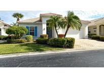 White house with blue shutters, palm trees, and a brick driveway at 7160 Rue De Palisades # 4, Sarasota, FL 34238