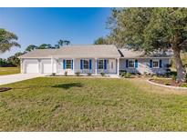 Charming one-story home with blue shutters, a well-manicured lawn, and a two car garage at 25413 Prada Dr, Punta Gorda, FL 33955