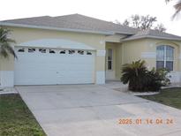 Tan one-story house with a white garage door and landscaping at 4325 Wordsworth Way, Venice, FL 34293