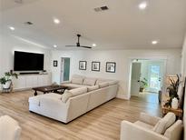 Bright living room features light hardwood floors, large sectional sofa, and a view to the backyard at 565 Sandy Hook Rd, Palm Harbor, FL 34683