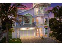 Three-story house with pastel exterior, a two-car garage, and palm trees at 112 Mangrove Ave, Anna Maria, FL 34216