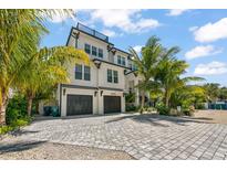 Two-story home with a white exterior, dark gray roof, and a large driveway at 3015 Avenue E, Holmes Beach, FL 34217