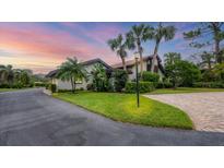 Beautifully landscaped home with a lush green lawn, mature palm trees, and a winding driveway at 3102 Windrush Bourne # 4, Sarasota, FL 34235