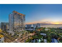 Aerial view of a modern high-rise building at sunset, offering stunning water views at 668 Quay Commons # 1102, Sarasota, FL 34236