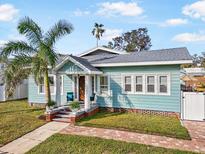 Charming bungalow with a light blue facade, brick walkway, and lush landscaping at 1812 7Th W Ave, Bradenton, FL 34205