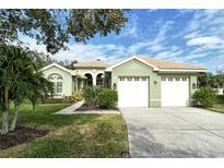 Light green house with two-car garage, landscaping, and a paved driveway at 5097 Faberge Pl, Sarasota, FL 34233