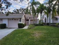 Pink condo with attached garage and lush green lawn at 5492 Hampstead Heath # 11, Sarasota, FL 34235