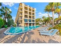 Inviting pool area with lounge chairs, located adjacent to a charming three-story building at 6326 Midnight Pass Rd # 101, Sarasota, FL 34242
