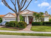 Single-story home with tile roof, lush landscaping, and a two-car garage at 7207 Saint Johns Way, University Park, FL 34201