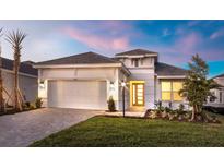 White one-story house with gray roof, two-car garage, and landscaped lawn at 16415 Isola Pl, Bradenton, FL 34211