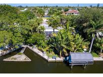 Aerial view of canal-front home with lush landscaping, boat lift, and private dock at 5140 Windward Ave, Sarasota, FL 34242