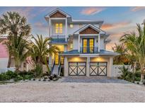 Two-story house with a light blue metal roof, two-car garage, and landscaped yard at 518 Spring Ave, Anna Maria, FL 34216