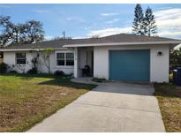 Ranch-style home with teal garage door and landscaped lawn at 2510 Parma St, Sarasota, FL 34231