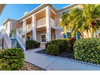 Two-story condo building with lush landscaping and a walkway at 4202 Caddie E Dr # 102, Bradenton, FL 34203