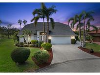 Lovely house with palm trees and a landscaped yard at dusk at 6170 Misty Oaks Dr, Sarasota, FL 34243