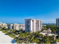 Aerial view of beachfront condo building with pool and lush landscaping at 1212 Benjamin Franklin Dr # 305, Sarasota, FL 34236