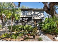 Front view of a two-story home showcasing a balcony and mature trees at 1423 Landings Pl # 59, Sarasota, FL 34231