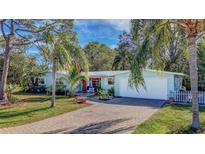 Light blue house with a paved driveway, palm trees, and a white picket fence at 2338 Lynn St, Sarasota, FL 34231