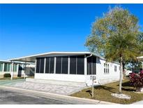 White mobile home with screened porch, paved patio, and landscaping at 3411 Spanish Oak Ter, Sarasota, FL 34237