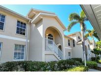 Tan two-story condo building with white trim, lush landscaping, and a stairway at 4250 Players Pl # 2625, Sarasota, FL 34238