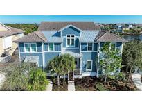 Two-story home with blue siding, metal roof, and palm trees at 307 Compass Point Dr # 101, Bradenton, FL 34209