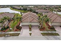 Aerial view of two-unit home with tile roofs, two-car garages, and landscaped yards at 20289 Benissimo Dr, Venice, FL 34293