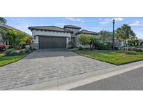 Single-story home with paver driveway, two-car garage, and landscaped yard at 328 Aria Dr, Nokomis, FL 34275