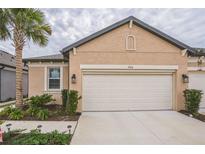 Tan house with white garage door, landscaping, and palm trees at 5914 Fiore Dr, Bradenton, FL 34208