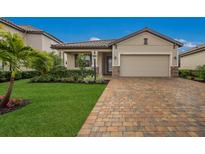 Single-story home with a landscaped lawn, paver driveway, and two-car garage at 6527 Clairborne Ln, Bradenton, FL 34211