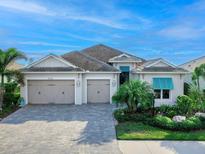 Two-story home with light taupe exterior, two-car garage, and landscaped yard at 8253 Grande Shores Dr, Sarasota, FL 34240