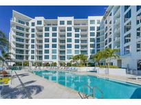 Luxury condo building featuring a pristine pool with lounge chairs and lush tropical landscaping at 111 S Pineapple Ave # 708, Sarasota, FL 34236