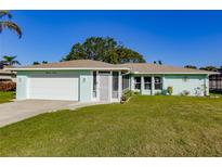 Light teal house with white garage door and well-manicured lawn at 1312 Lucaya Ave, Venice, FL 34285