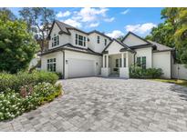 Two-story home with white exterior, gray paver driveway, and landscaping at 2174 Mcclellan Pkwy, Sarasota, FL 34239