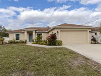Tan house with brown roof, landscaping, and a two-car garage at 4352 Adelaide Ave, North Port, FL 34288