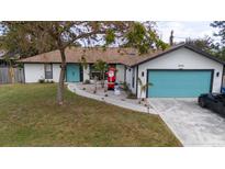 Updated single-story home with teal garage door and landscaped yard at 1008 Euclid Rd, Venice, FL 34293